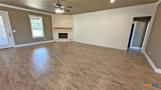 unfurnished living room with ornamental molding, a fireplace, wood-type flooring, and ceiling fan