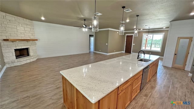 kitchen with hanging light fixtures, sink, a large island with sink, and light hardwood / wood-style floors