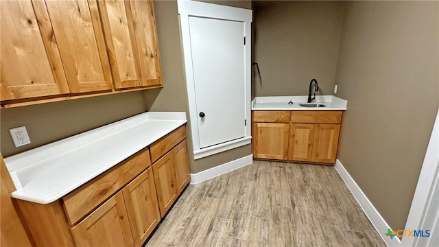 clothes washing area featuring sink and light hardwood / wood-style flooring