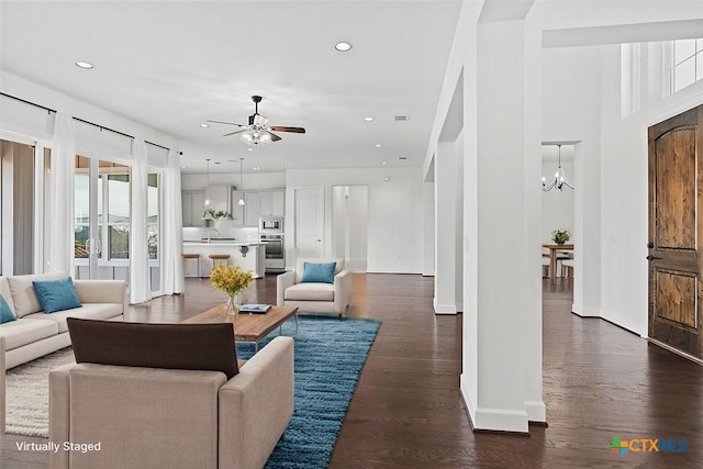 living room featuring sink, ceiling fan with notable chandelier, and dark wood-type flooring