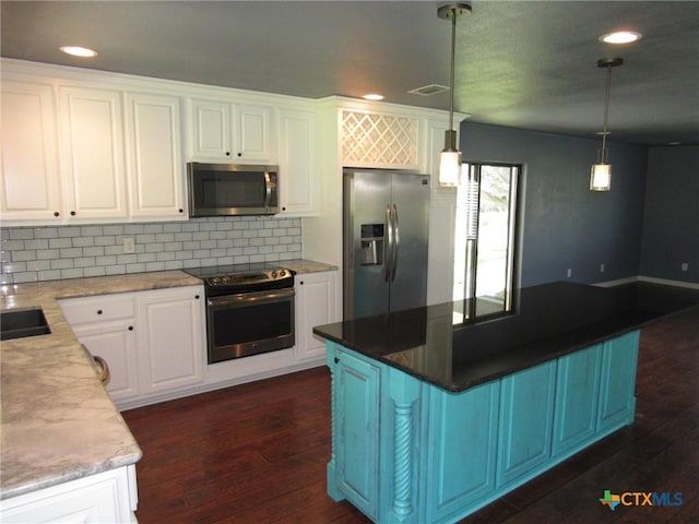 kitchen featuring stainless steel appliances, hanging light fixtures, white cabinets, and decorative backsplash