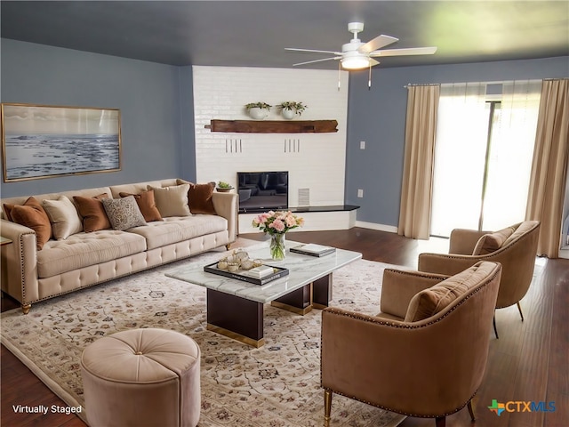 living room with hardwood / wood-style flooring, a brick fireplace, and ceiling fan