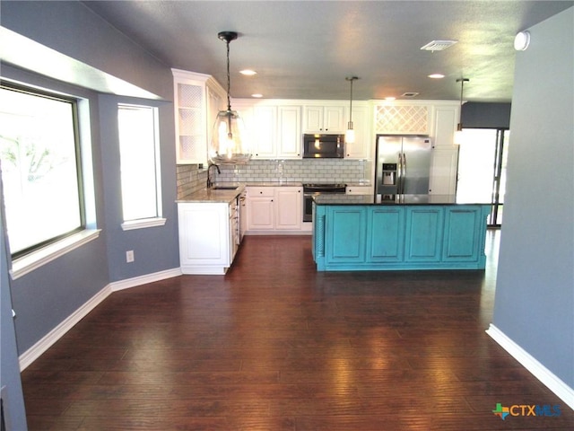 kitchen with sink, hanging light fixtures, appliances with stainless steel finishes, white cabinets, and backsplash