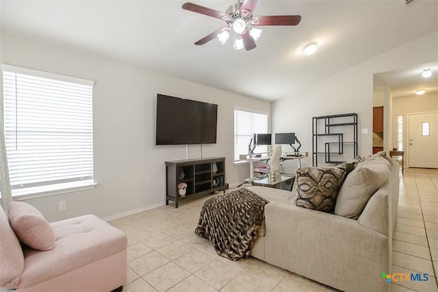 living area with lofted ceiling, ceiling fan, baseboards, and light tile patterned flooring