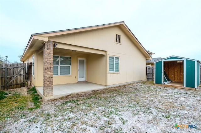 back of property featuring an outbuilding, a patio area, fence, and a storage shed