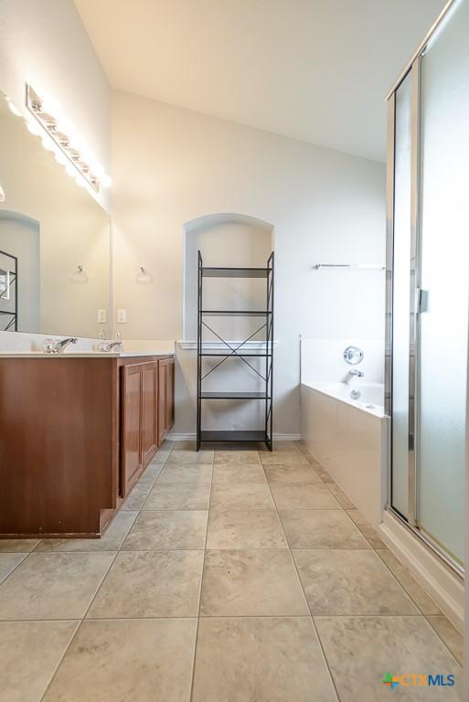 bathroom featuring baseboards, a shower with shower door, tile patterned flooring, vanity, and a bath