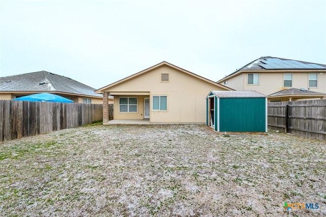 back of property featuring a shed, a patio, a fenced backyard, and an outbuilding