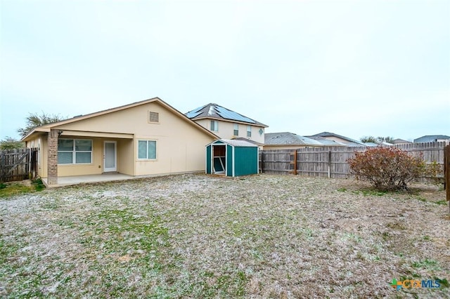 rear view of house with a patio area, a fenced backyard, a storage unit, and an outbuilding