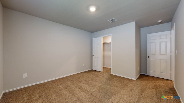 unfurnished bedroom with a walk in closet, light carpet, and a closet