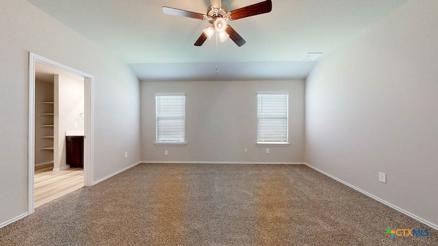 spare room with ceiling fan, light colored carpet, and vaulted ceiling