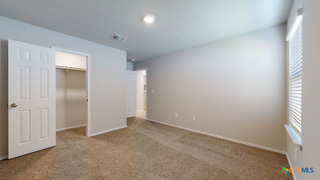 unfurnished bedroom featuring light carpet and a closet