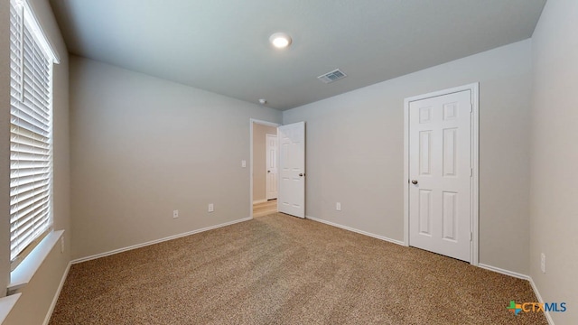 unfurnished bedroom featuring carpet flooring and multiple windows