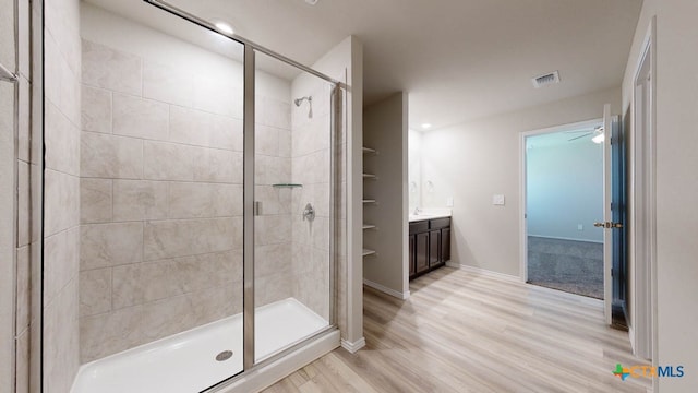 bathroom featuring ceiling fan, vanity, wood-type flooring, and walk in shower