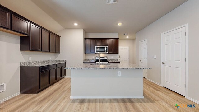 kitchen with a center island with sink, light hardwood / wood-style flooring, and appliances with stainless steel finishes