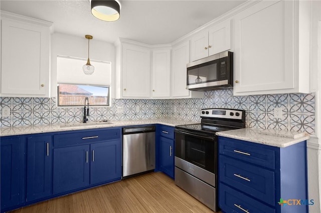 kitchen featuring sink, white cabinets, blue cabinetry, hanging light fixtures, and appliances with stainless steel finishes