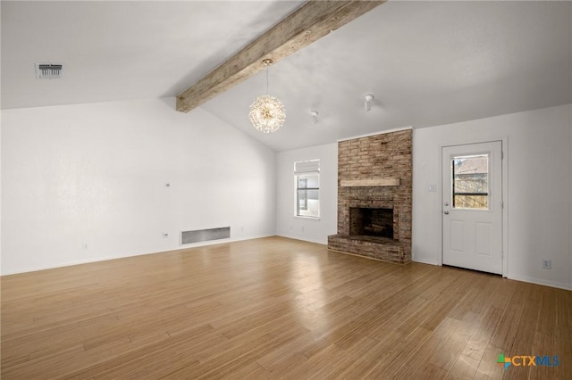 unfurnished living room with an inviting chandelier, vaulted ceiling with beams, light hardwood / wood-style flooring, and a stone fireplace