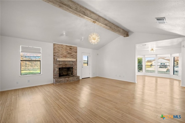 unfurnished living room featuring a fireplace, lofted ceiling with beams, a notable chandelier, and light hardwood / wood-style flooring