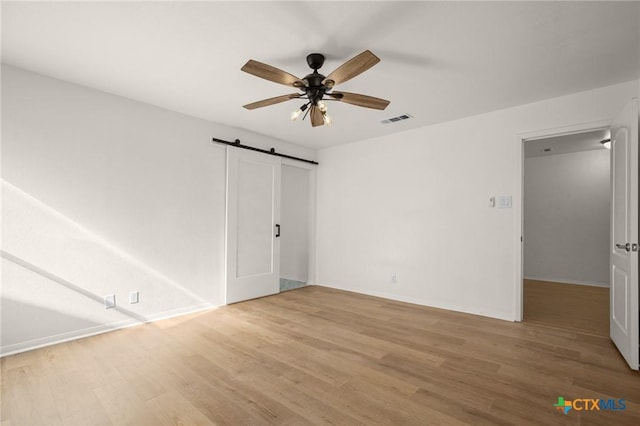 interior space featuring ceiling fan, a barn door, and wood-type flooring