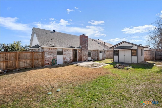 rear view of property with a lawn, a patio, and a shed