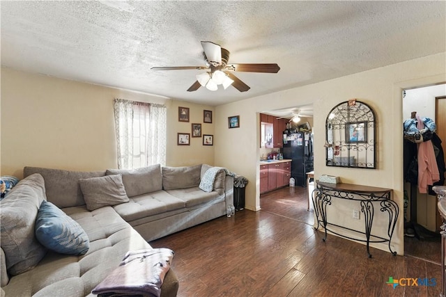 living room featuring ceiling fan, a textured ceiling, and dark wood-type flooring