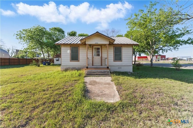 bungalow-style house with fence, metal roof, crawl space, and a front lawn
