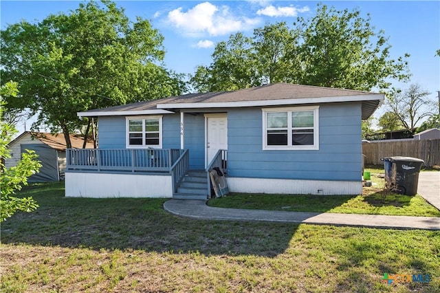 view of front of house with fence, a wooden deck, and a front lawn