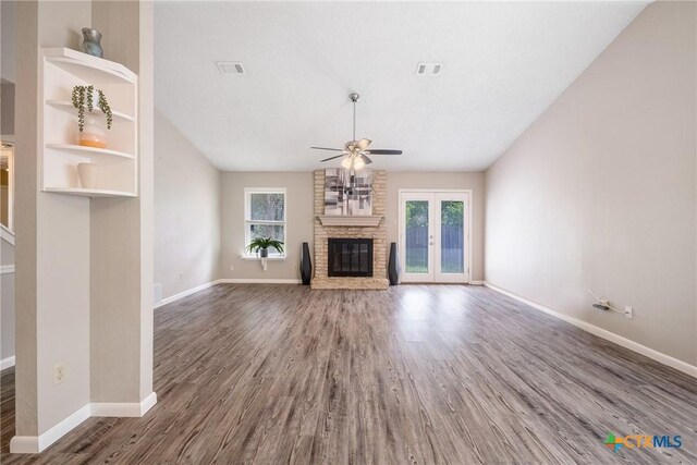 7503 Islander Dr, Austin, TX 78749 - unfurnished living room with ceiling fan, plenty of natural light, a large fireplace, wood finished floors, and vaulted ceiling