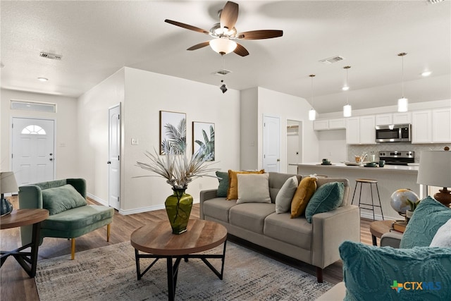 living room with hardwood / wood-style flooring, ceiling fan, and a textured ceiling