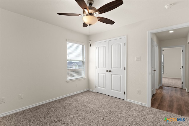 unfurnished bedroom with a closet, ceiling fan, and dark carpet