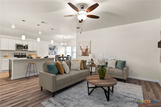 living room featuring dark hardwood / wood-style flooring and ceiling fan with notable chandelier