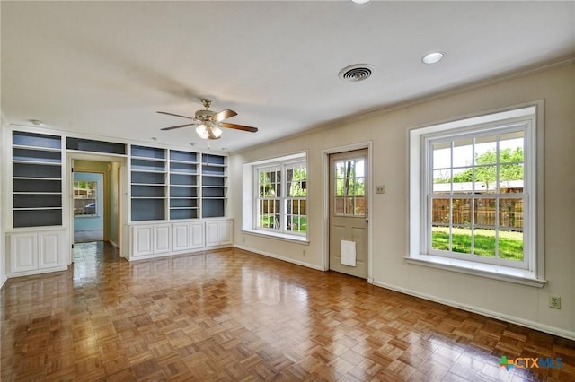 interior space featuring visible vents, built in features, baseboards, ceiling fan, and crown molding
