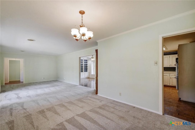 carpeted empty room featuring ceiling fan with notable chandelier, baseboards, and ornamental molding