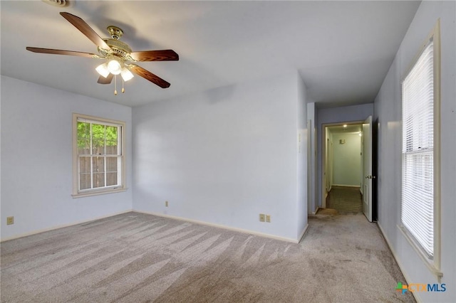 empty room featuring a ceiling fan and light carpet