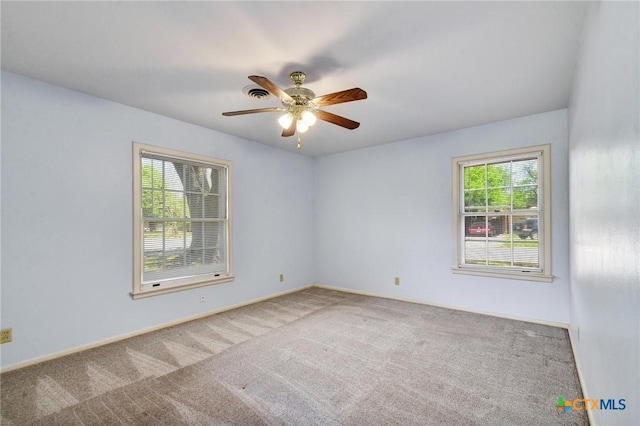 empty room featuring carpet flooring, a ceiling fan, plenty of natural light, and visible vents