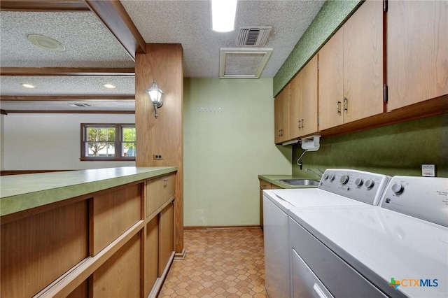 laundry room with washing machine and dryer, visible vents, a textured ceiling, and a sink