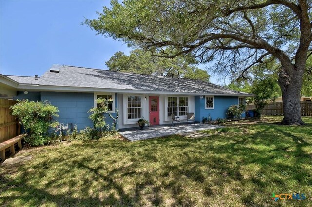 rear view of house featuring an attached garage, a yard, a patio area, and fence