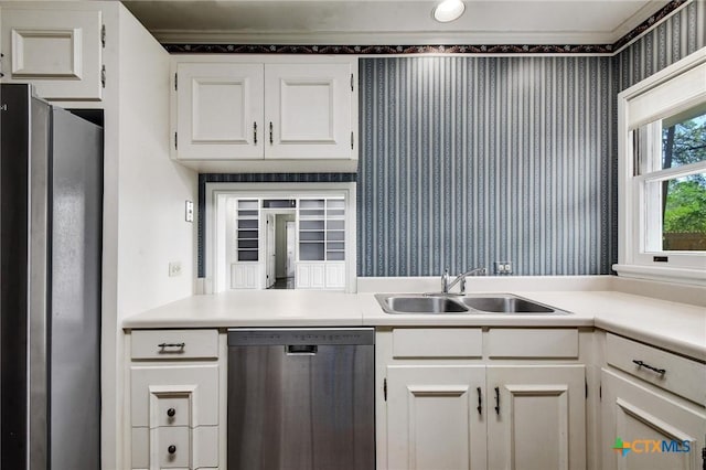 kitchen with wallpapered walls, a sink, white cabinetry, and stainless steel appliances