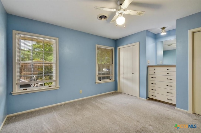 unfurnished bedroom featuring carpet floors, a ceiling fan, visible vents, and baseboards