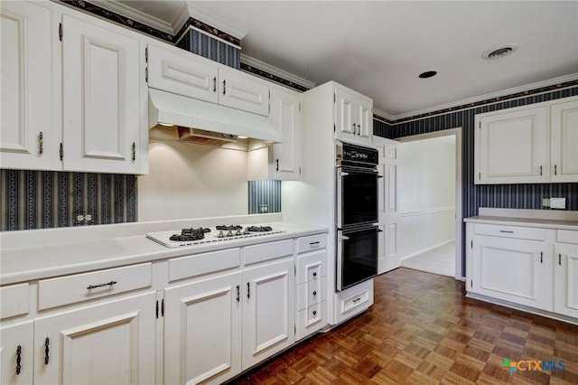 kitchen featuring under cabinet range hood, white gas cooktop, dobule oven black, and wallpapered walls