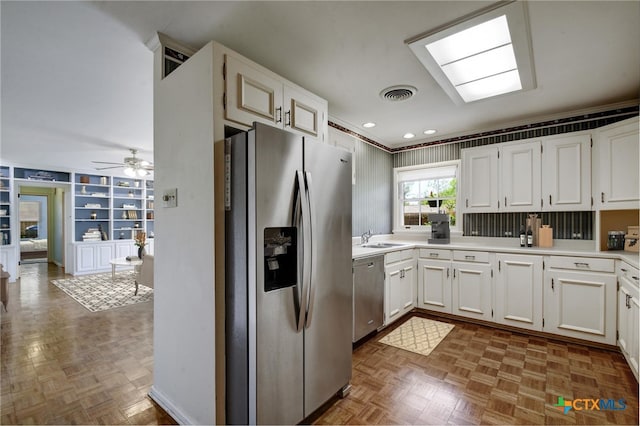 kitchen with visible vents, appliances with stainless steel finishes, a sink, light countertops, and built in shelves