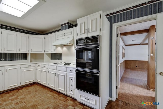 kitchen with crown molding, dobule oven black, a wainscoted wall, under cabinet range hood, and light countertops