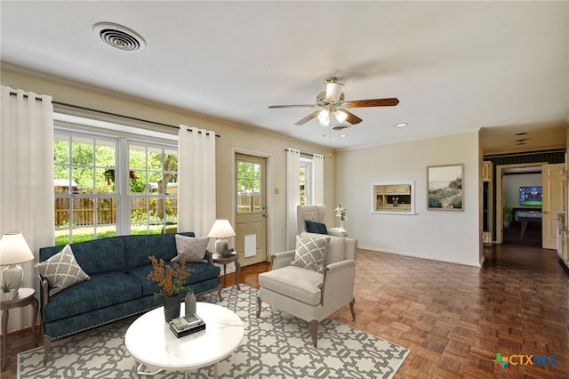 living room with ornamental molding, baseboards, visible vents, and ceiling fan