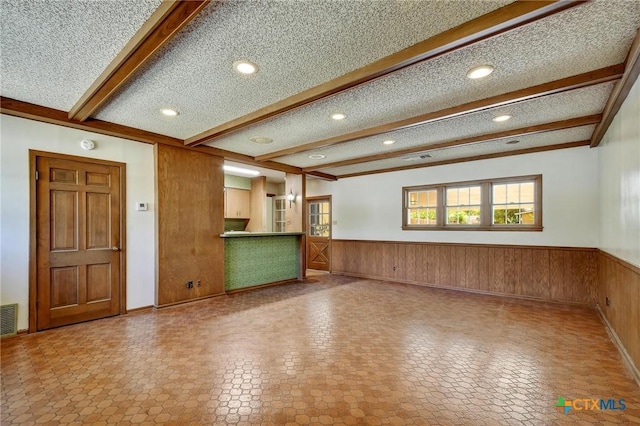 unfurnished living room featuring beamed ceiling, wooden walls, wainscoting, and recessed lighting
