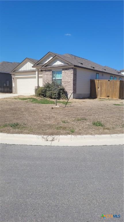 view of front of property with brick siding, an attached garage, board and batten siding, fence, and driveway