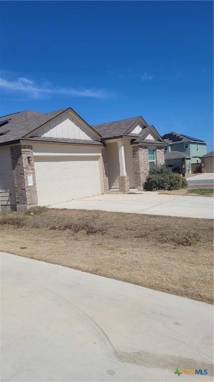 view of front of house featuring driveway, brick siding, board and batten siding, and an attached garage