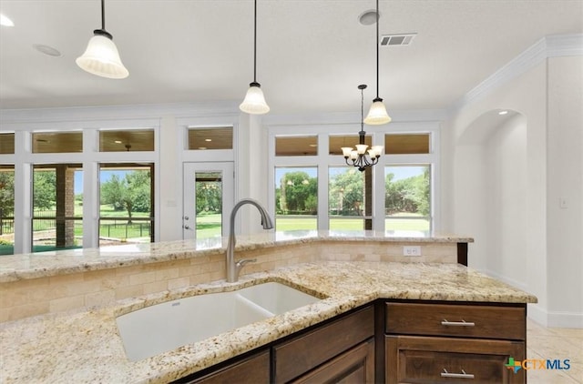 2901 Chisholm Trl, Salado, TX 76571 - kitchen with light stone counters, hanging light fixtures, dark brown cabinets, a chandelier, and ornamental molding