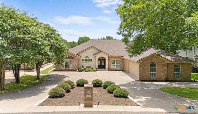 2901 Chisholm Trl, Salado, TX 76571 - french country inspired facade with curved driveway, brick siding, a garage, and roof with shingles