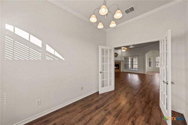 empty room with dark hardwood / wood-style floors, ornamental molding, ceiling fan with notable chandelier, and french doors