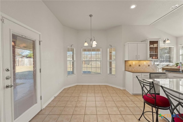 kitchen with light tile patterned flooring, white cabinets, an inviting chandelier, decorative backsplash, and vaulted ceiling