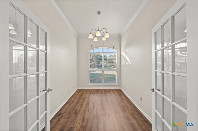 unfurnished dining area with french doors, dark wood-type flooring, a chandelier, and ornamental molding